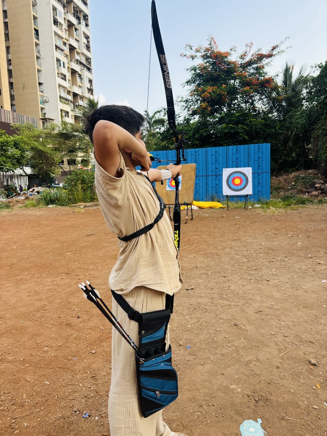 A man aiming a bow and arrow outdoors, showing focus